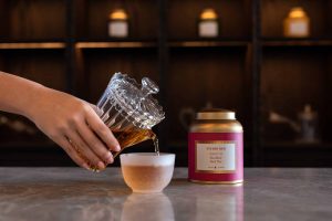 Hand pour studio red wellness tea into glass cup